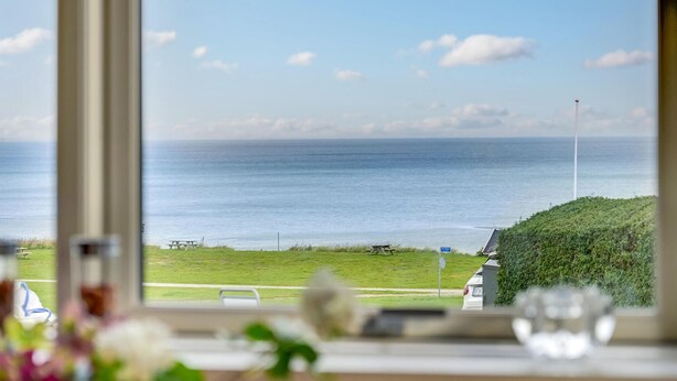 A view of the sea from a window overlooking a grassy area with picnic tables. - 1 bedroom awesome home in Allingåbro (Allingåbro)