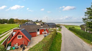 A coastal property with a red house, a gravel driveway, and a view of the sea. - 1 bedroom awesome home in Allingåbro (Allingåbro)