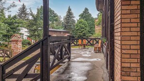 A covered outdoor area with a wooden staircase leading to a brick building.