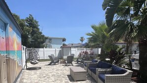 A patio area with wicker furniture, a swing chair, and a mural on the wall.