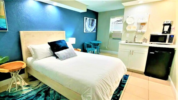 A bedroom with a bed, bedside table, lamp, and a small potted plant.