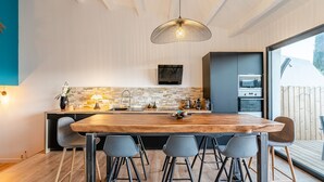 A modern kitchen with a wooden island, bar stools, and a hanging light fixture. - Villa Design D'architecte - 10 Personnes - Jacuzzi, Piscine ,tennis (Cassis)