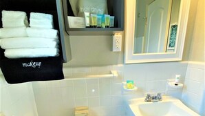 A bathroom with a toilet, sink, and a shelf with toiletries. - Tranquil King Deluxe (Daytona Beach)