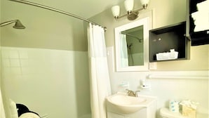 Une salle de bain équipée d’une douche, de toilettes, d’un lavabo et d’un miroir au-dessus du lavabo.