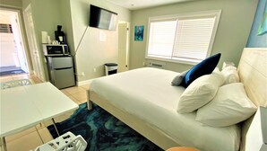Une chambre à coucher avec un lit, un bureau, une chaise, une télévision et une fenêtre.