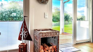 A room with a fireplace, a wreath on the wall, and a view of the outdoors. - Awesome apartment in Büsum with sauna (Büsum)