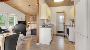 Een moderne keuken met witte kasten, een inbouwoven en een eethoek met een tafel en stoelen.