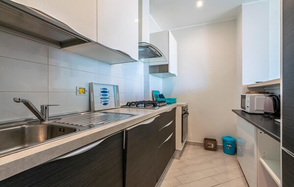 A compact kitchen with a stainless steel sink, a gas stove, and a microwave. - 2 bedroom stunning apartment in Marinella di Sarzana (Marinella di Sarzana)