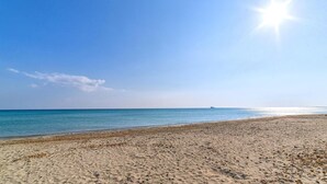 Una playa con cielo despejado y mar tranquilo.