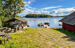 A lakeside cabin with a dock, picnic tables, and a red building. - Nice home in Rörvik with WiFi (Rörvik)
