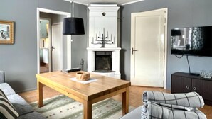 A living room with a wooden table, a sofa, a fireplace, and a television. - Nice home in Rörvik with WiFi (Rörvik)