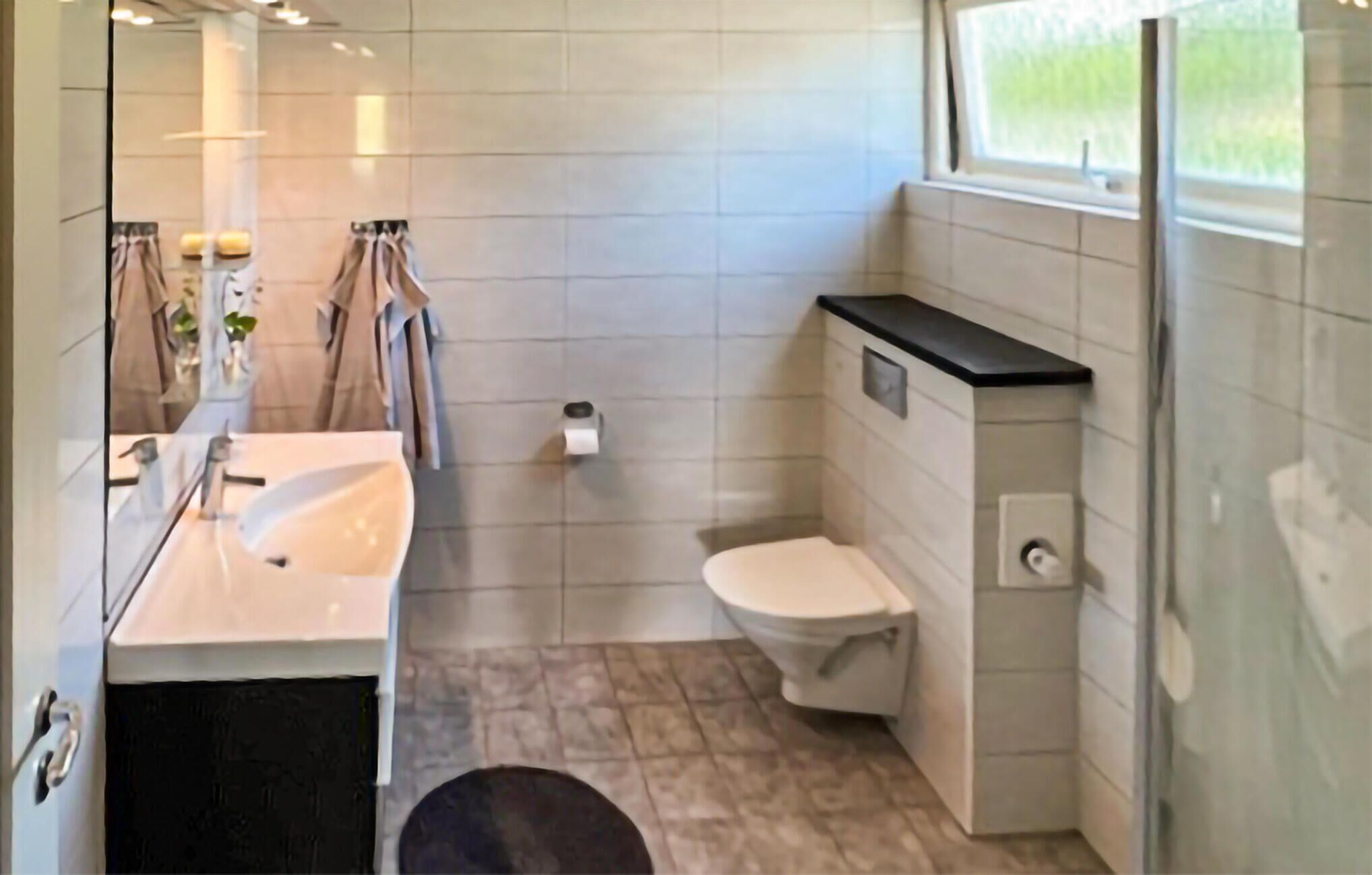 A modern bathroom with a white sink, toilet, and shower area.