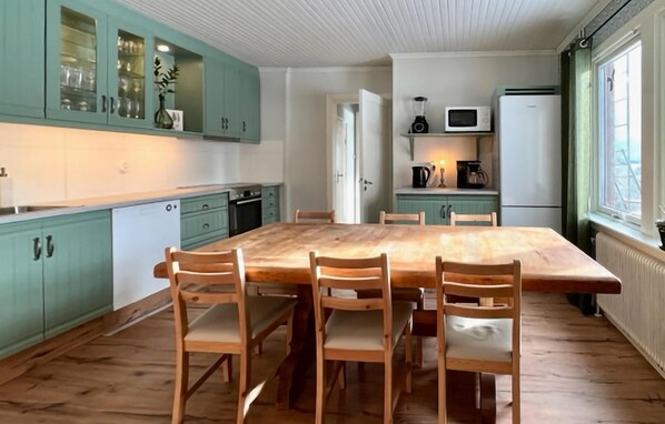 A kitchen with a wooden table and chairs, teal cabinets, and a white refrigerator. - Nice home in Rörvik with WiFi (Rörvik)