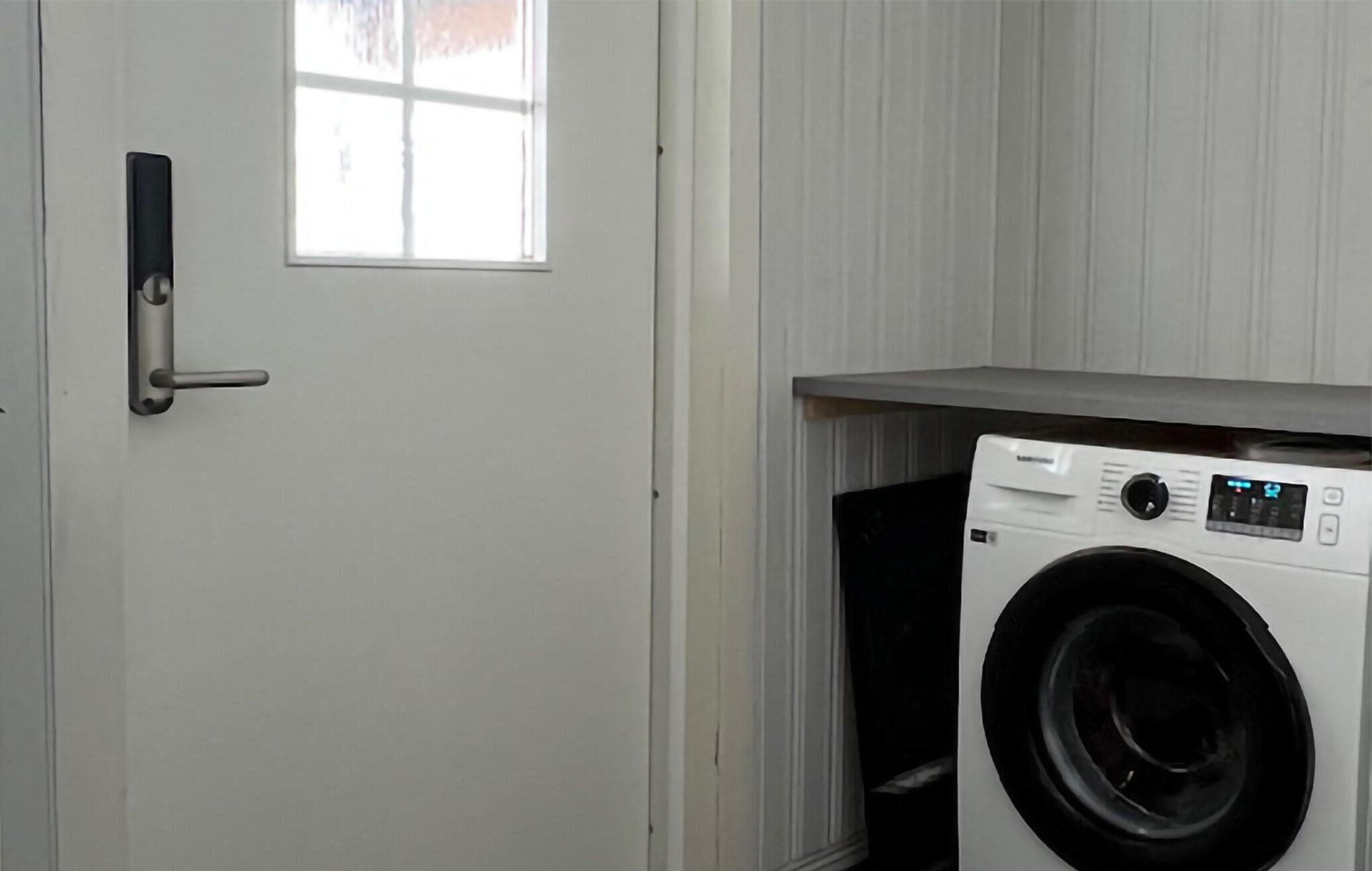 A laundry room with a washing machine, a door, and a window.