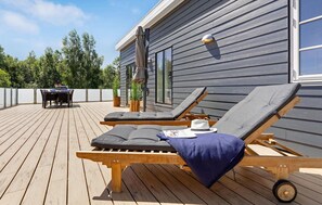 A wooden deck with two sun loungers, a table, and chairs. - 2 bedroom amazing home in Rødby (Rødby)