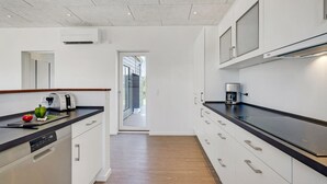 A modern kitchen with white cabinetry, a black countertop, and a coffee machine. - 2 bedroom amazing home in Rødby (Rødby)