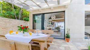An outdoor dining area with a table set for two, a wooden bench, and a potted plant. - Lovely home in Sutivan (Sutivan)