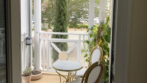 Une terrasse couverte avec une table et deux chaises, un pot de fleurs et une vue sur la végétation environnante.