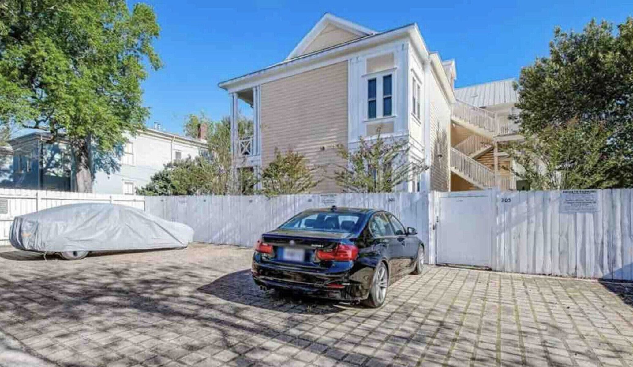 Uma casa de dois andares com um carro coberto na entrada.