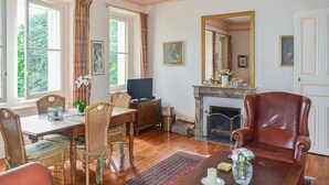 A traditional living room with a fireplace, a dining area with wicker chairs, and a leather armchair. - 1 bedroom stunning apartment in Ocquerre (Ocquerre)