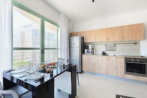 Cozinha moderna com área de refeições, grandes janelas e vista para edifícios.