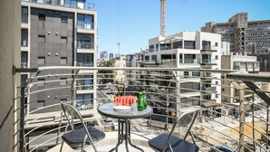 A balcony with a table, chairs, and a view of a construction site with a crane. - Mamad Modern 1BR w/ Style, City Views & Beach (Tel Aviv-Yafo)