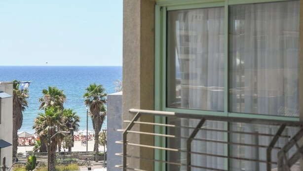 A balcony with a view of the sea, palm trees, and a beach. - Mamad Modern 1BR w/ Style, City Views & Beach (Tel Aviv-Yafo)