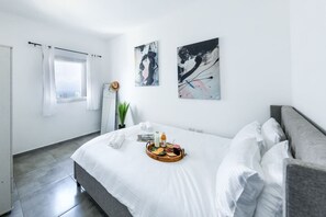 Une chambre d’hôtel moderne avec un grand lit, un plateau de petit-déjeuner et des œuvres d’art abstraites accrochées aux murs.