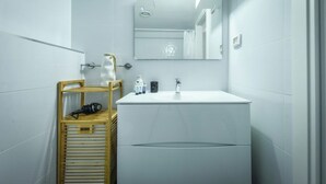 Un bagno moderno con lavandino bianco, specchio e ripiano in legno con articoli da toilette.