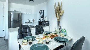 Una cucina moderna con un tavolo da pranzo apparecchiato per quattro persone, completa di sedie, frigorifero e microonde.