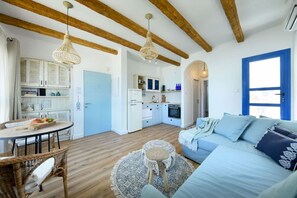 Un intérieur moderne avec des poutres apparentes, une cuisine, un coin repas avec une table ronde et un canapé bleu.