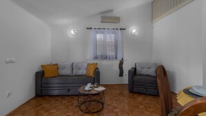 Ein Wohnzimmer mit einer Couch, einem kleinen runden Tisch und einem Fenster mit Jalousien.