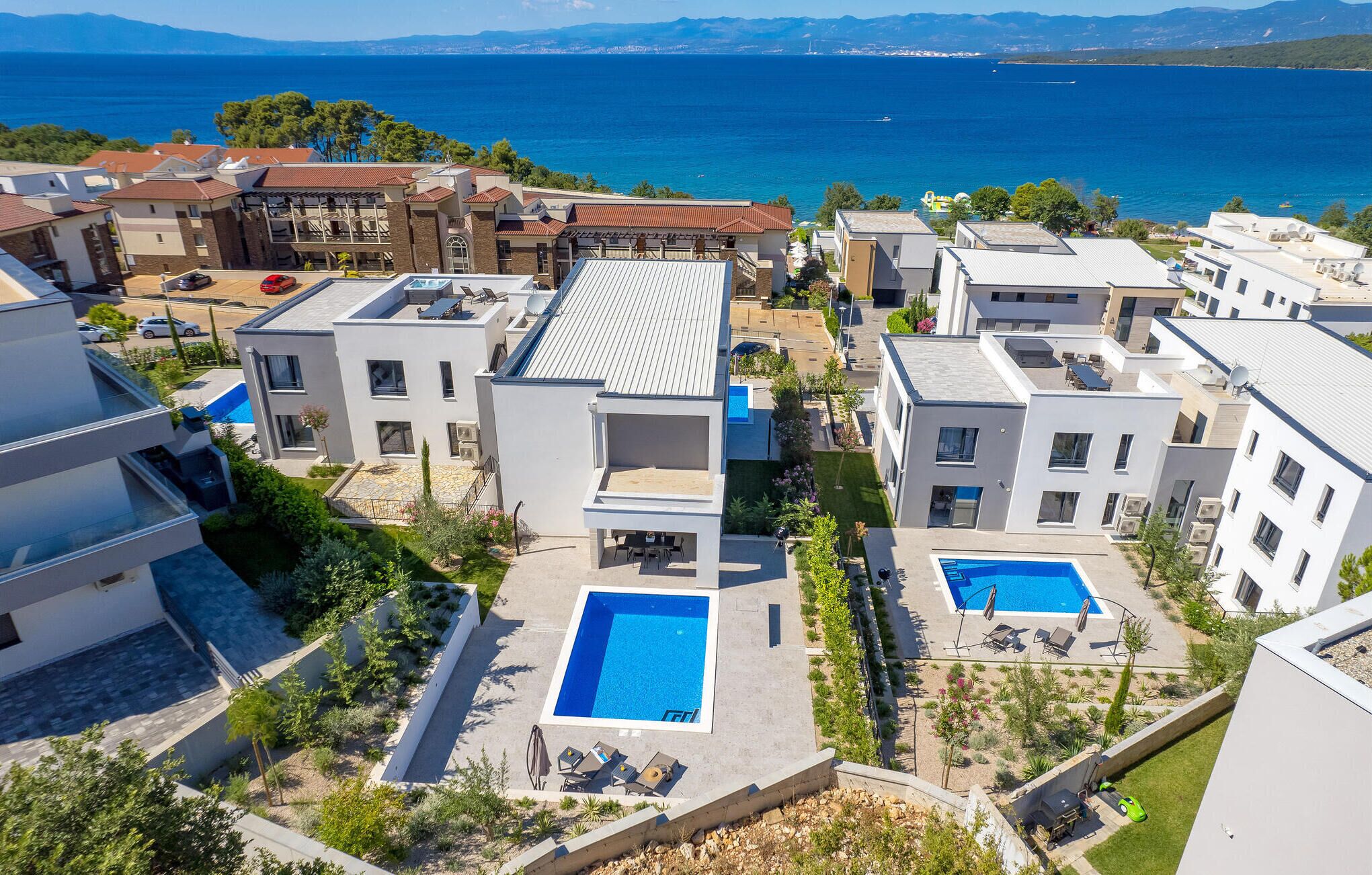 Et moderne boligområde med flere bygninger, en swimmingpool og havudsigt.