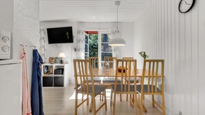 Une cuisine moderne avec des meubles blancs, un four encastré et un téléviseur fixé au-dessus du plan de travail.