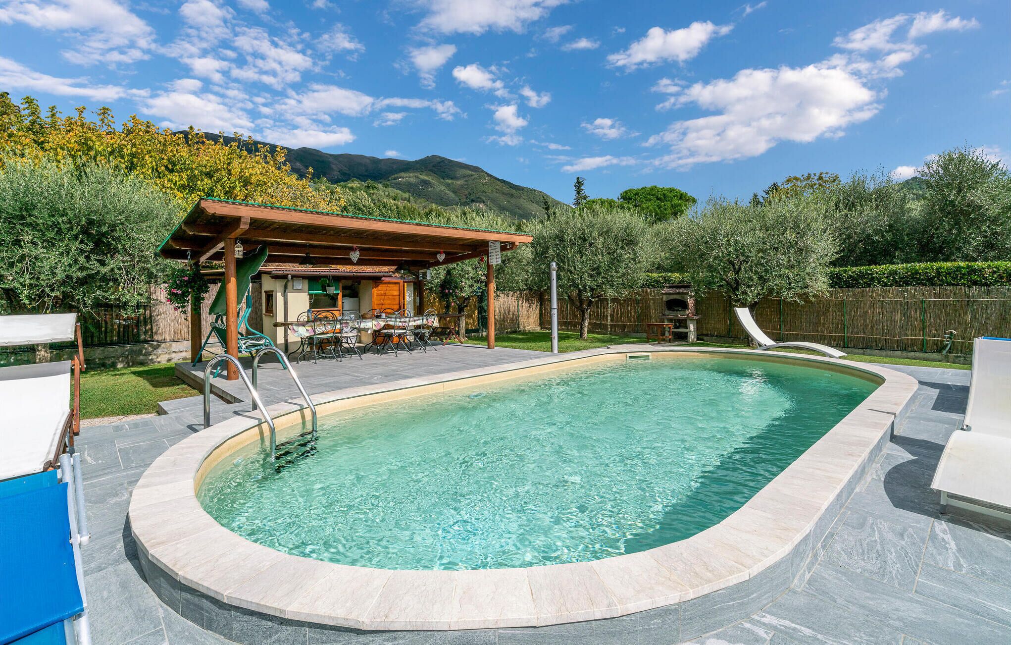 A swimming pool with a slide, surrounded by a patio area with outdoor furniture and a pergola.