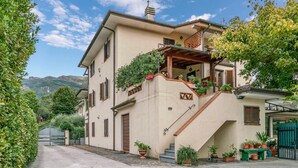Ein zweistöckiges Haus mit Balkon, Blumentöpfen und einer Treppe, die zum Eingang führt.