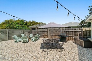 A backyard with a barbecue area, outdoor seating, and string lights. - Relaxed Beach Cottage, Steps to Sand, Near 30A & Pier Park (Panama City Beach)