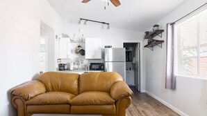 Ett modernt vardagsrum med en lädersoffa, ett matbord och ett kök i bakgrunden.