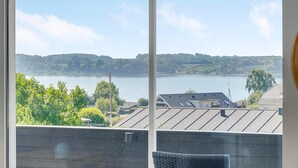 A view from a window overlooking a lake with buildings and greenery in the foreground. - 3 bedroom awesome home in Hejls (Hejls)