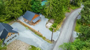Une maison à deux étages, dotée d’un toit en pente et entourée d’une forêt dense.