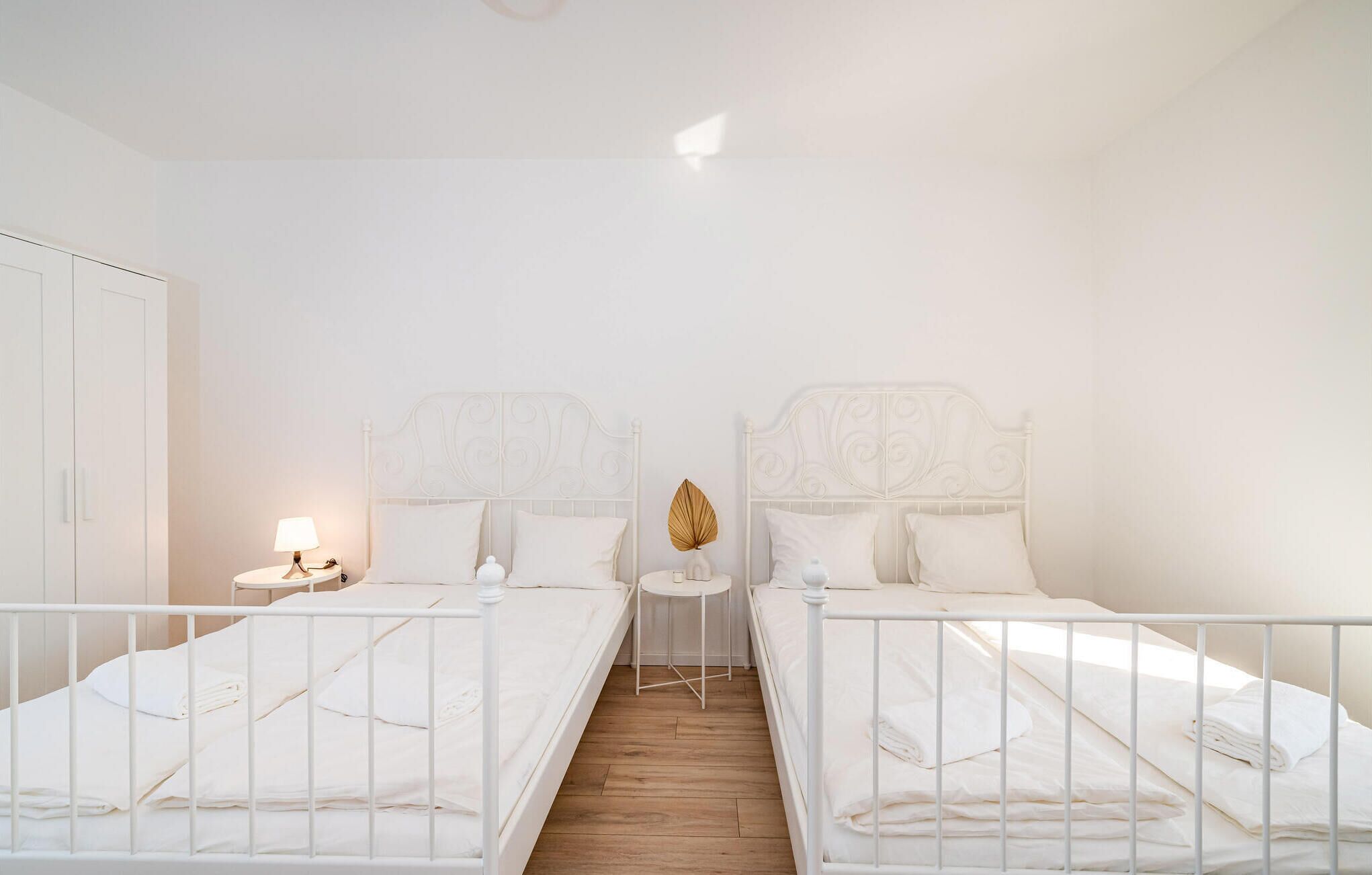 Une chambre double avec deux lits, une petite table ronde, une lampe et une armoire.