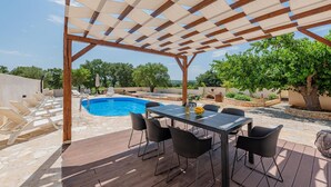 Un espace extérieur abrité comprenant une piscine, une terrasse en bois et des sièges.