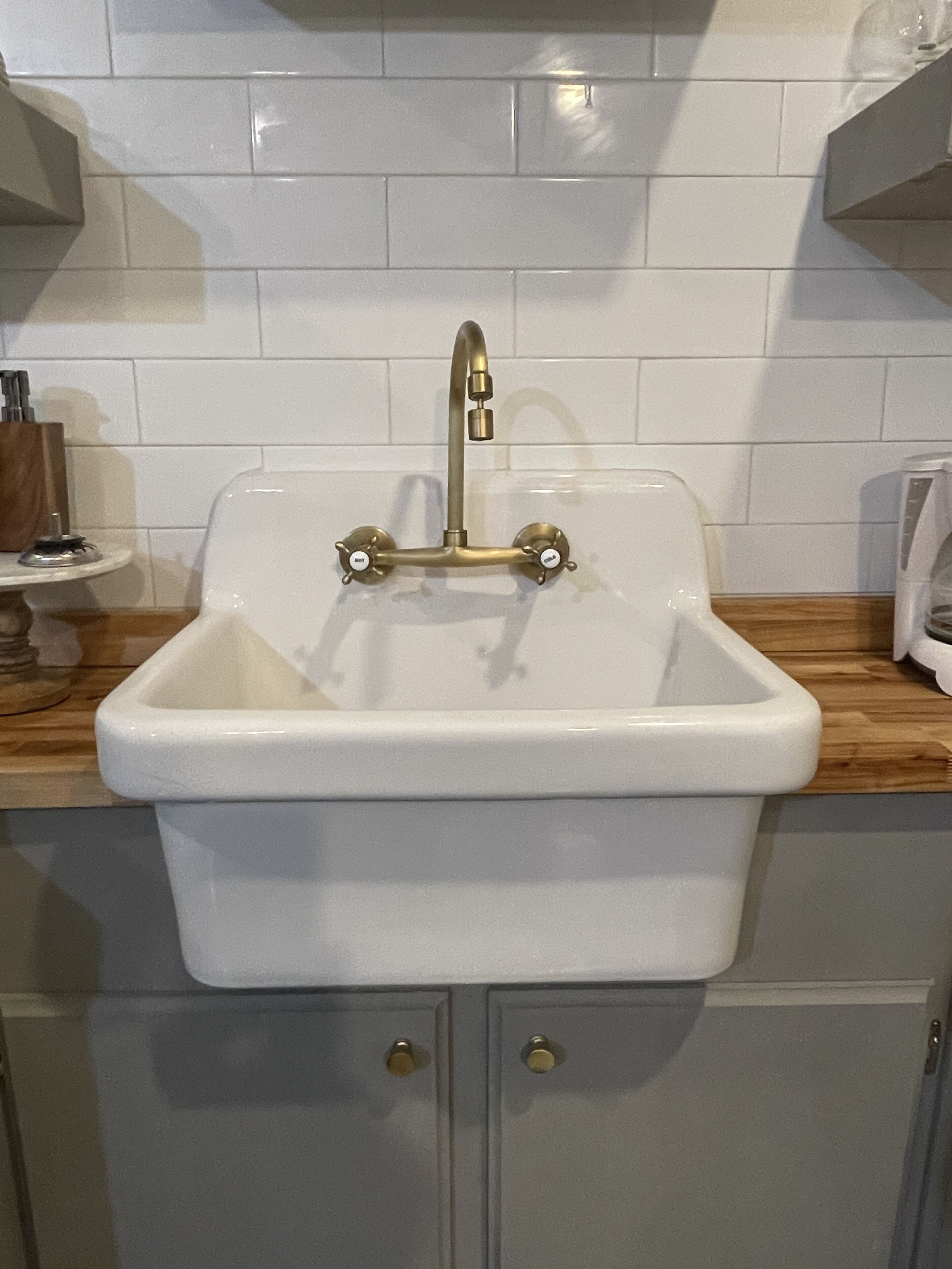 A kitchen sink with a single faucet, a wooden countertop, and a cabinet below.