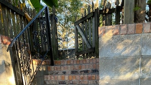 Un escalier en briques avec une rampe métallique, menant à une clôture en bois.