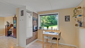 Una cocina moderna con horno empotrado, un comedor con mesa y sillas, y un amplio ventanal que ofrece vistas al exterior.