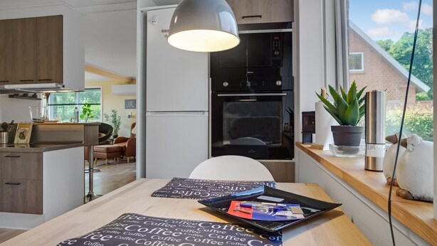 Una cocina moderna con horno integrado, un comedor con mesa y vistas al exterior.