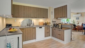 Una cocina moderna con armarios de madera, lavavajillas integrado e isla central con pileta.