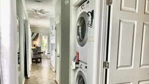 A laundry room with a front-loading washer and dryer, a ceiling fan, and a tiled floor. - Shore Beats Work condo @ Caribbean Dunes across from Crystal Beach - Snowbirds ❤️ (Destin)