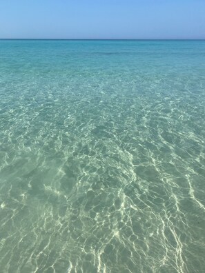 Agua turquesa transparente con reflejos suaves y superficie tranquila.