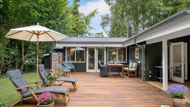 En terrasse med udendørs møbler, et bord og en potteplante.